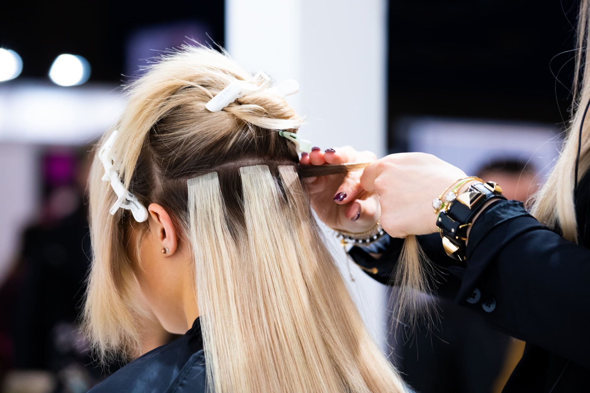 hairstylist installing invisi tape in hair extenions in salon
